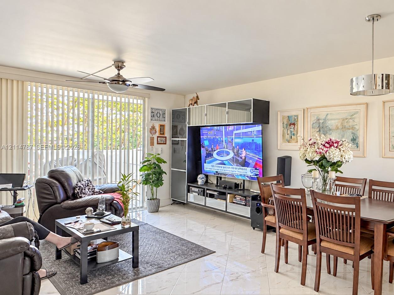 Open-concept area featuring polished tile flooring, integrated floor-to-ceiling media cabinetry, a modern ceiling fan, and a contemporary drum pendant light