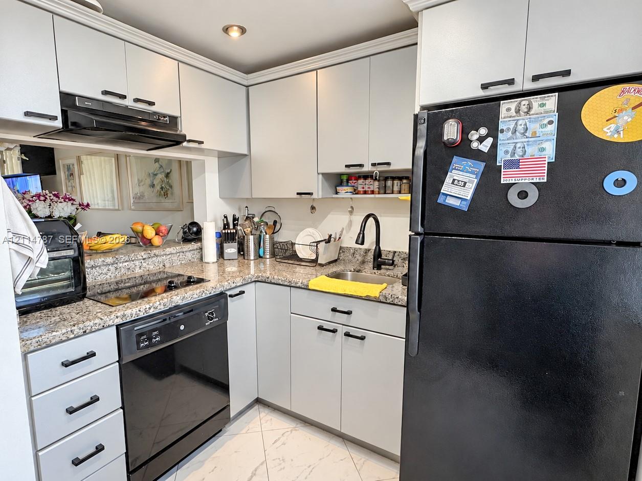 Kitchen featuring light-toned cabinetry with matte black hardware, stone-composite countertops, and a black faucet paired with an undermount sink