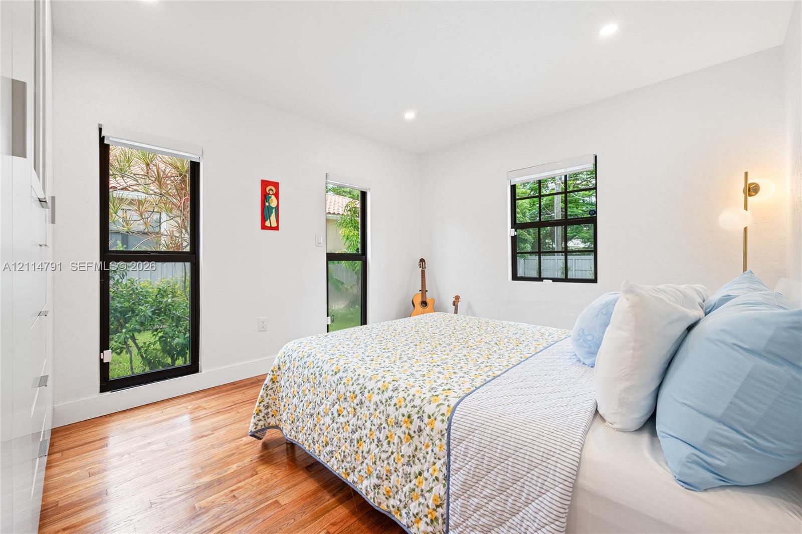 Room featuring wood-finish flooring, recessed lighting, white walls, and black-framed windows
