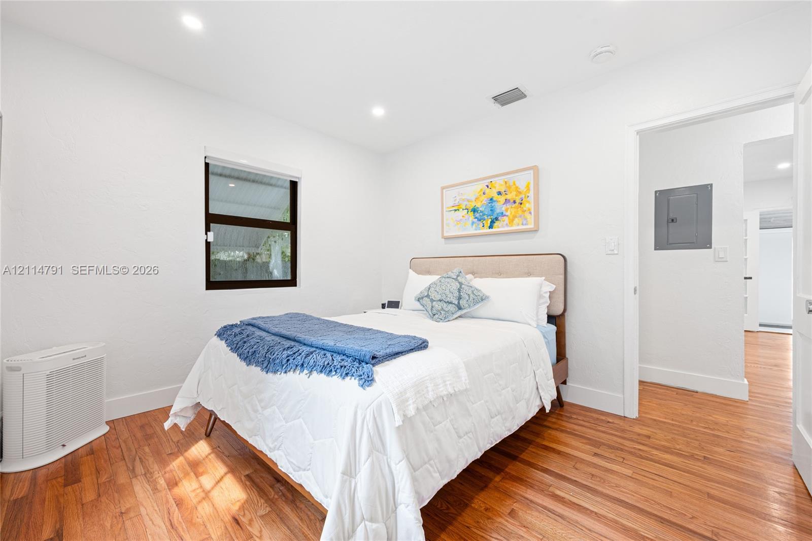 Neutral-toned interior featuring wood-finish flooring, recessed lighting, and a window with a dark frame
