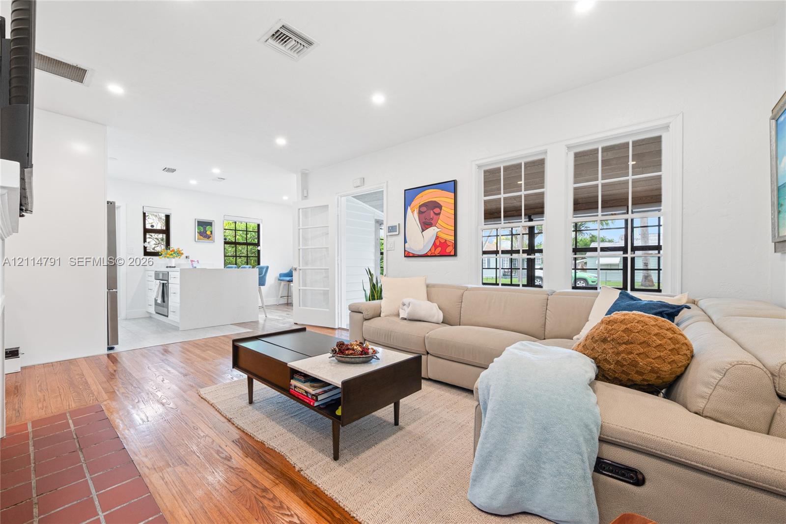 Open-concept interior featuring wood-finish flooring, recessed lighting, multi-pane windows, and a built-in kitchen island