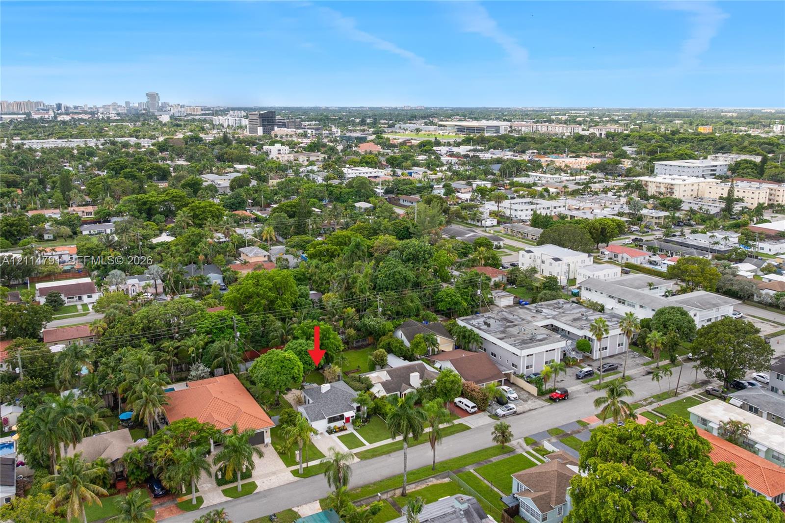 Aerial perspective featuring a residential lot with mature trees and a structured roofline, situated within a developed urban setting