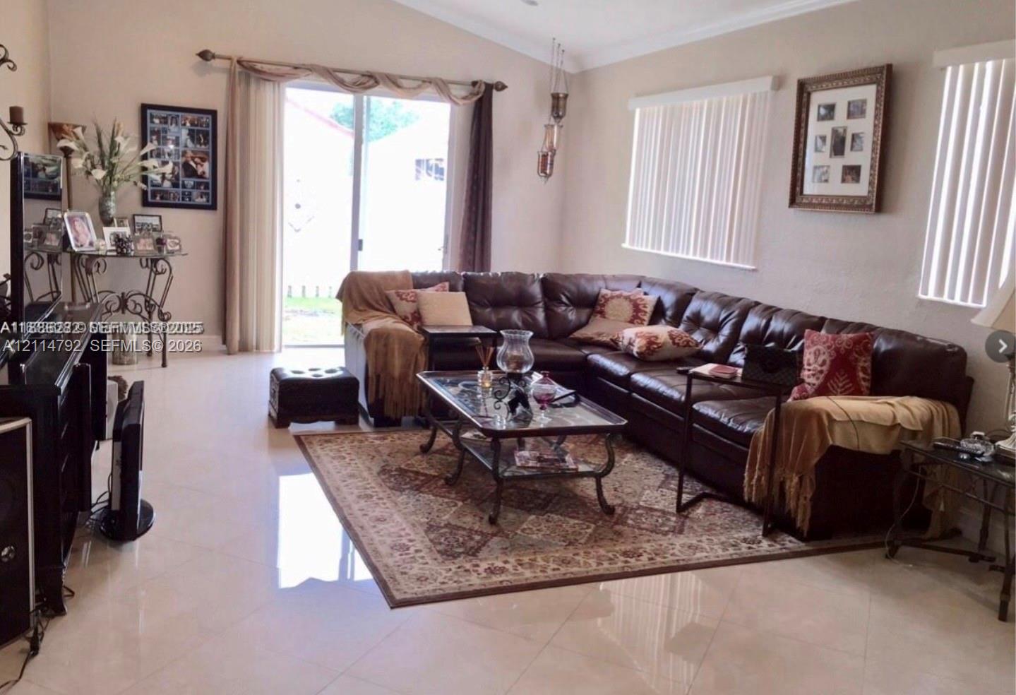 Living area featuring a vaulted ceiling, large-format tile flooring, and a sliding glass door providing access to the exterior