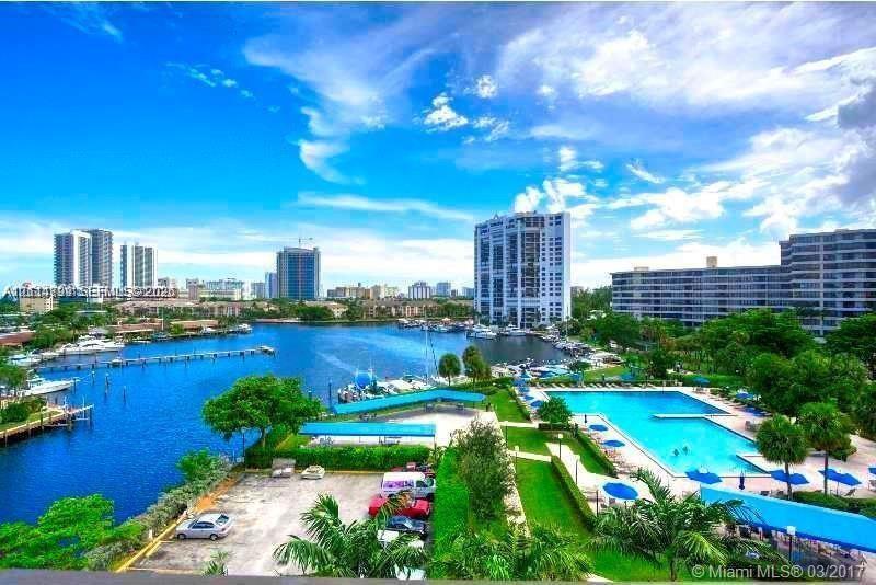 Waterfront complex featuring a swimming pool, paved surface parking, boat slips, and extensive green space