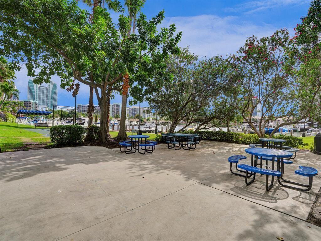 Paved outdoor common area featuring mature shade trees and manicured lawn space