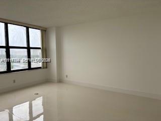 Neutral-toned interior space featuring polished tile flooring, white walls, and expansive windows with black frames