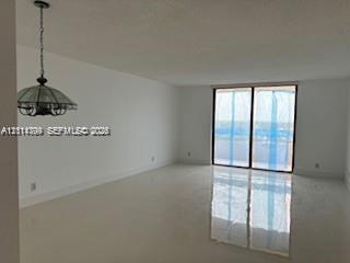 Open-concept interior featuring polished tile flooring, floor-to-ceiling sliding glass doors, and a decorative pendant light fixture