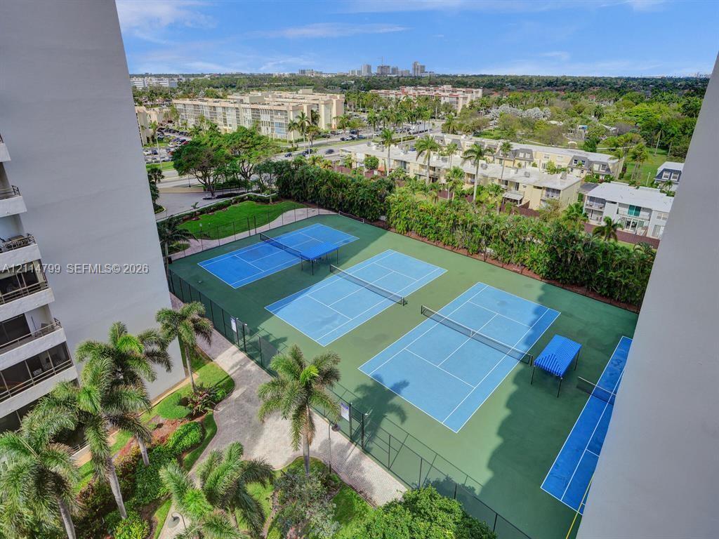 Multi-court tennis facility featuring fenced perimeters, paved walkways, and mature palm landscaping