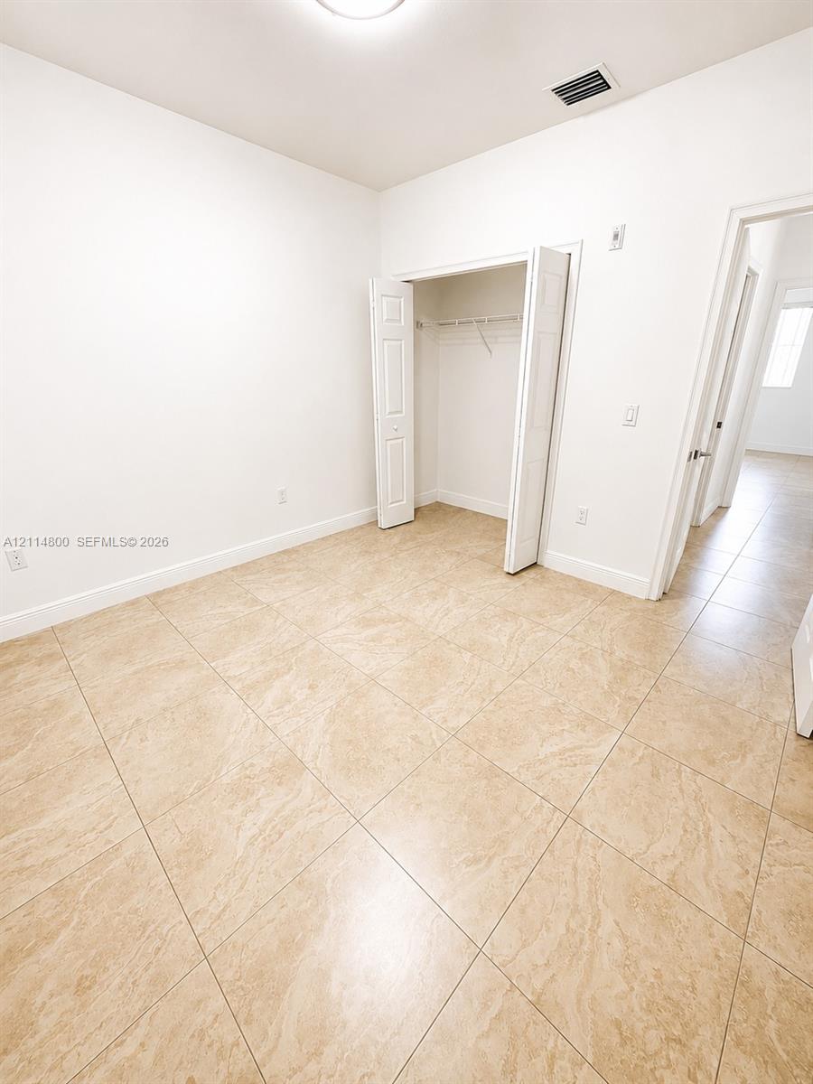 Neutral-toned tile flooring, white wall finish, and a closet with bifold doors