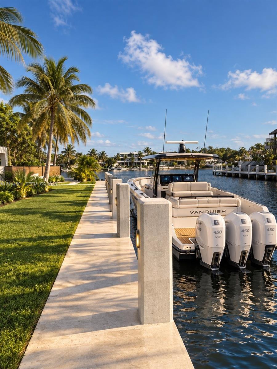 Deep-water dock featuring stone pavers, integrated post lighting, and mature palms