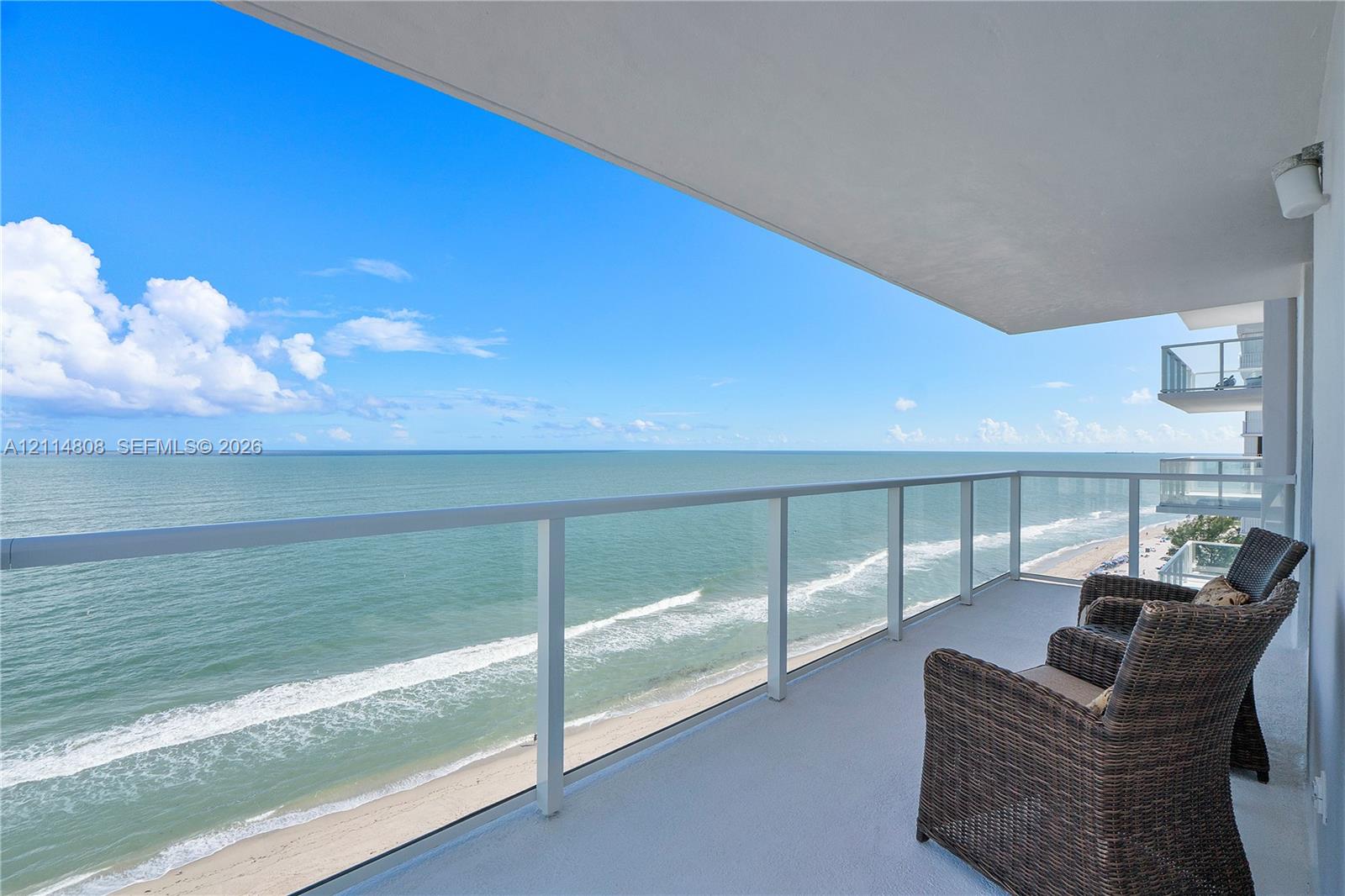 Covered balcony featuring a glass-panel railing and direct oceanfront exposure