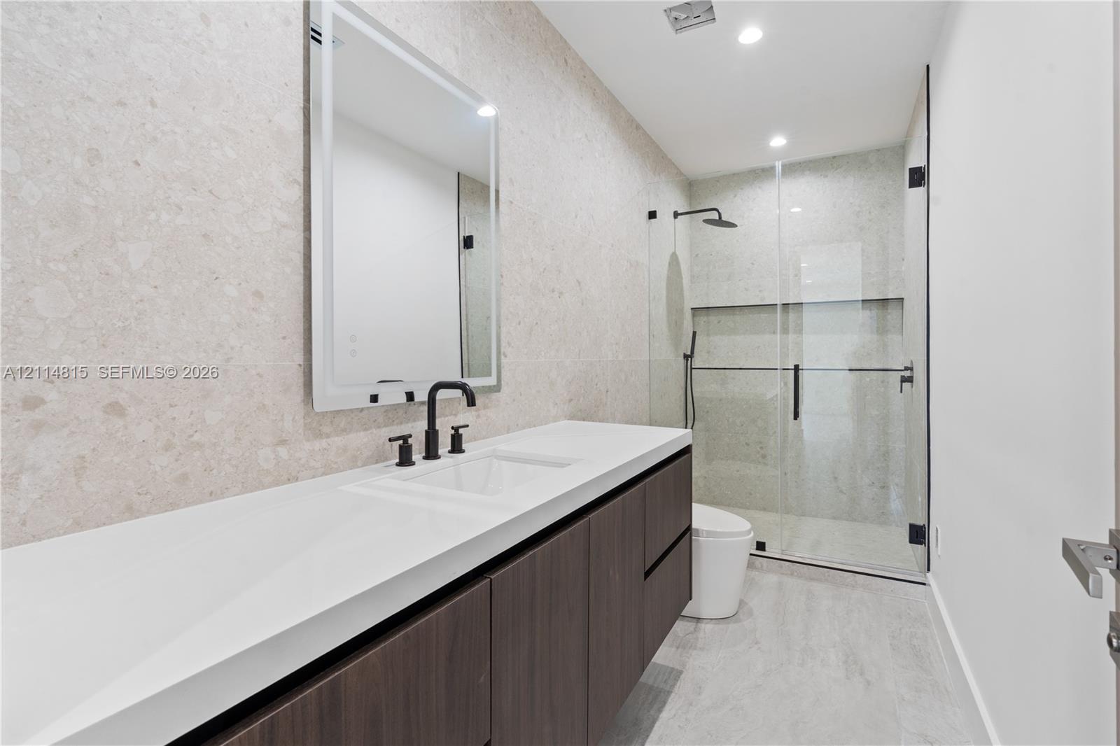 Floating dark wood-finish vanity with a rectangular sink, topped by a white countertop and a framed mirror