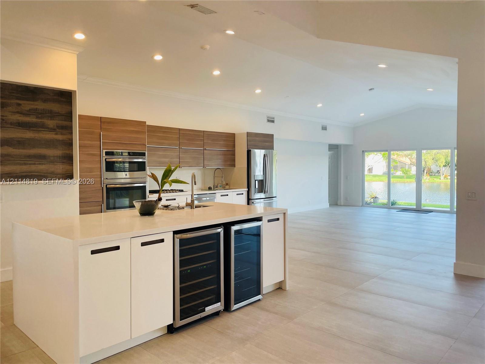 Kitchen featuring horizontal wood-grain cabinetry, quartz countertops, built-in dual beverage refrigerators, stainless steel double wall ovens, and porcelain tile flooring