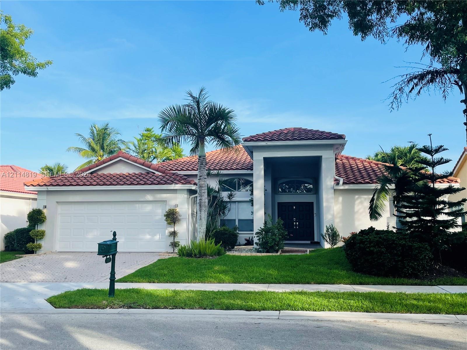Single-story residence featuring a terracotta-tiled roof, stucco exterior, paver driveway, two-car garage, and arched transom windows