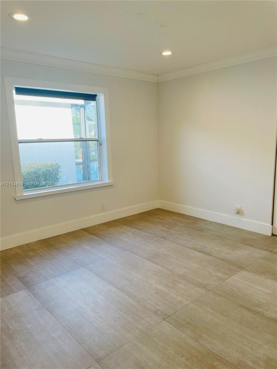 Neutral-toned interior featuring large-format tile flooring, recessed ceiling lighting, and a single-pane window with white trim