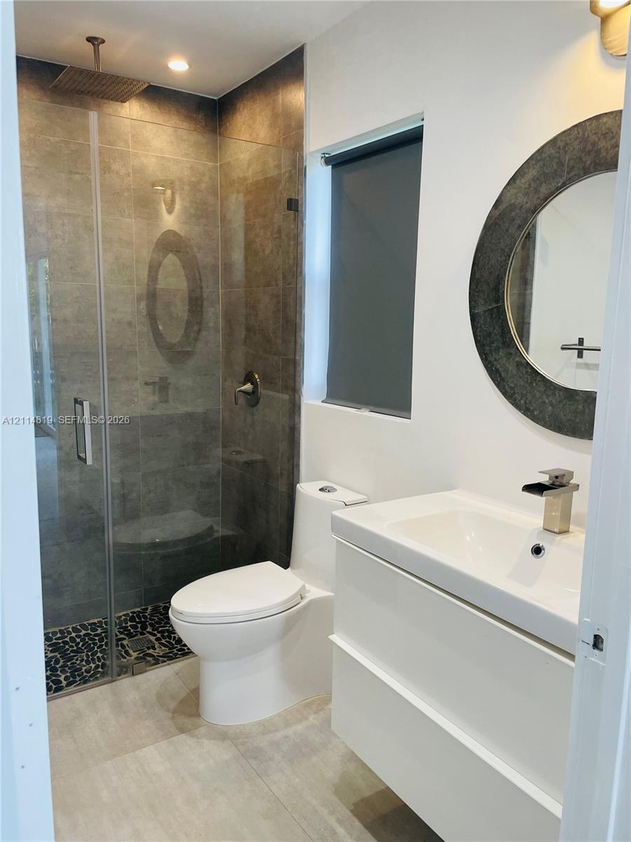 Modern floating vanity with a white basin and metallic faucet, complemented by a round framed mirror