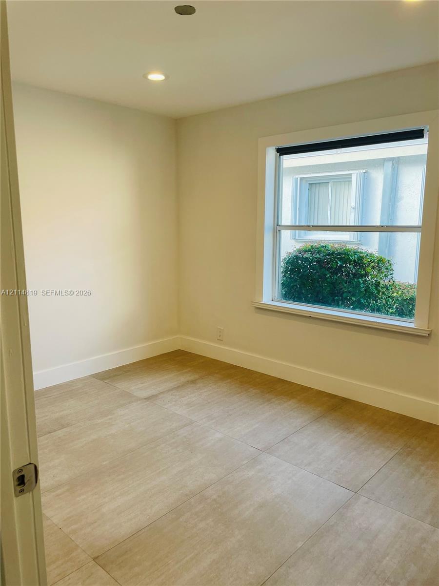 Interior space featuring neutral-toned tile flooring, recessed ceiling lighting, and a single-pane window with a minimalist frame