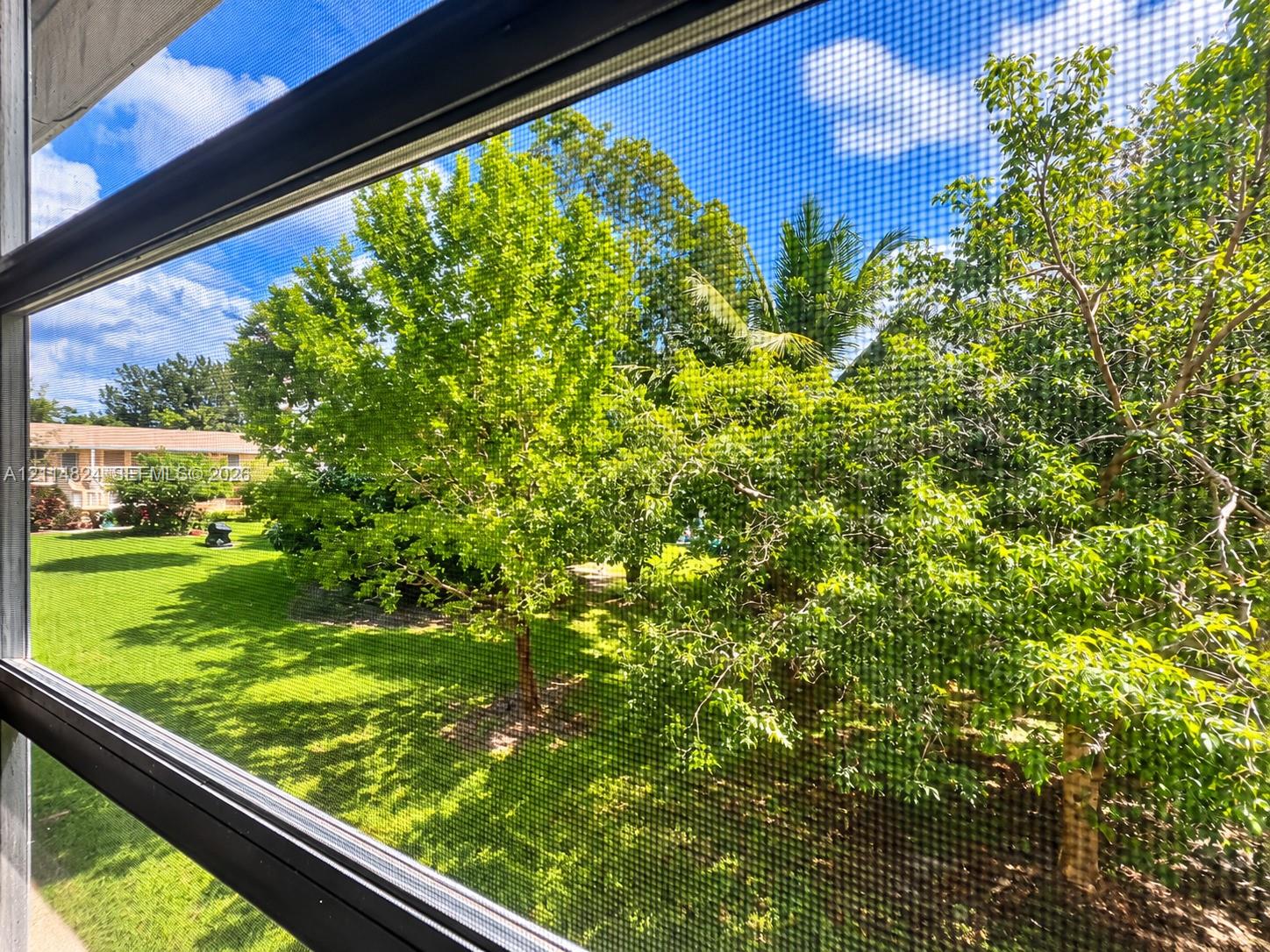 Screened enclosure featuring an expanse of lawn and mature trees
