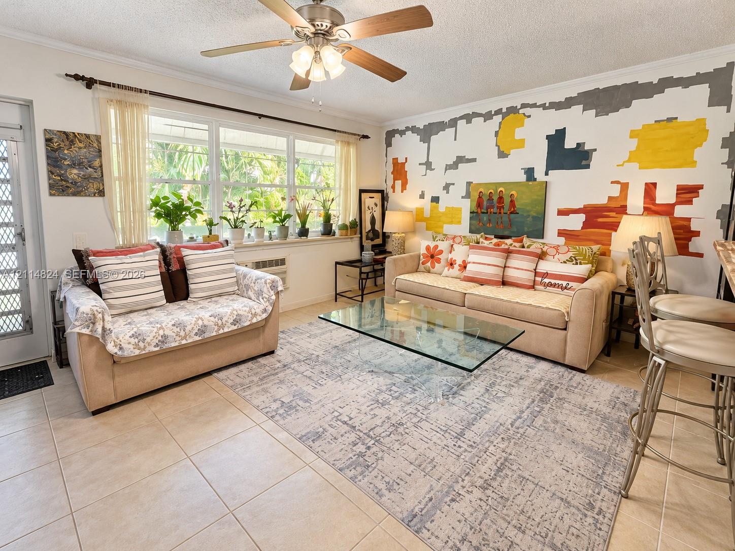 Living area featuring large windows with natural light, neutral ceramic tile flooring, and a ceiling fan with integrated lighting