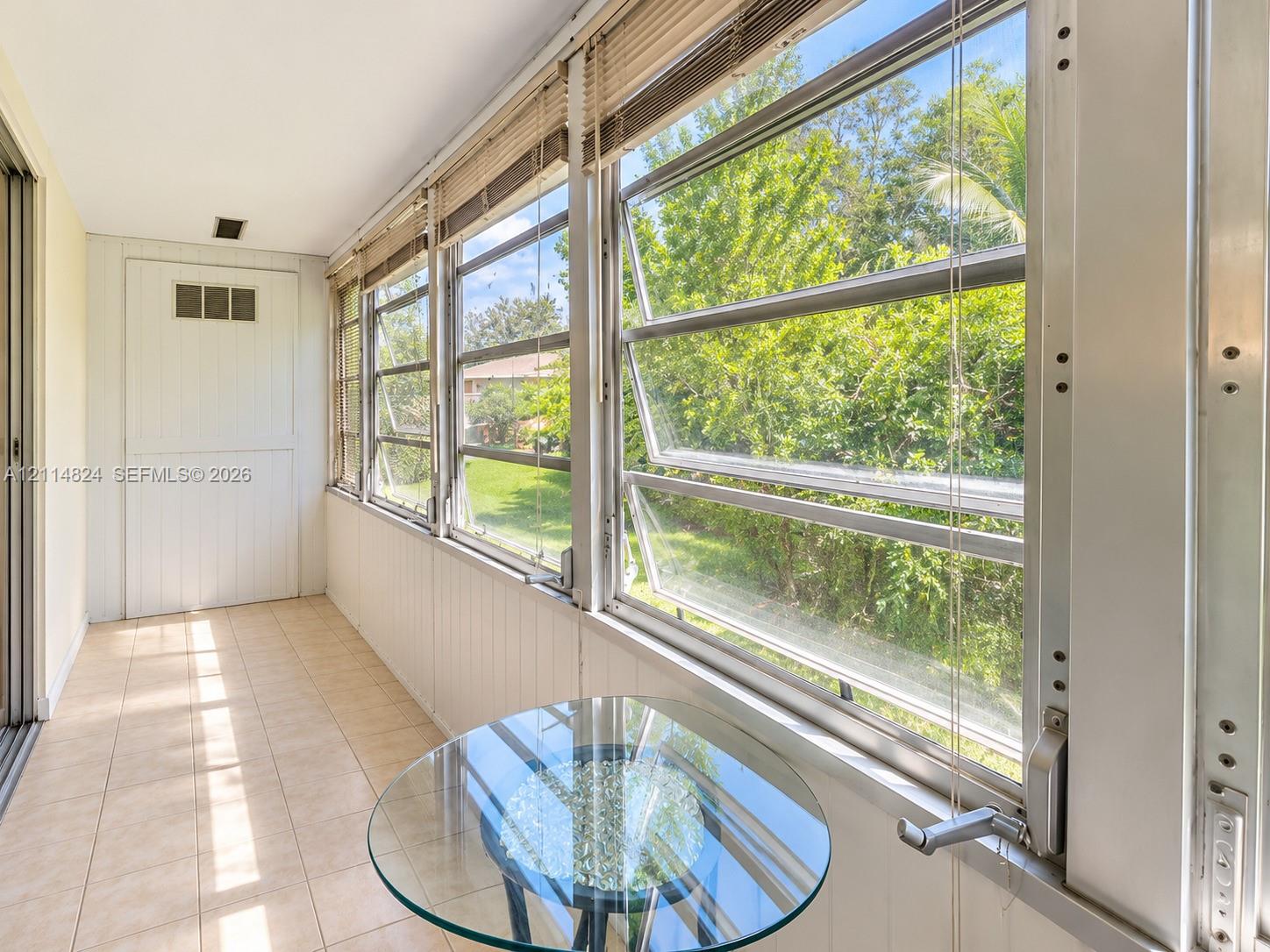 Enclosed sunroom featuring ceramic tile flooring, vertical wall paneling, and multiple awning-style windows