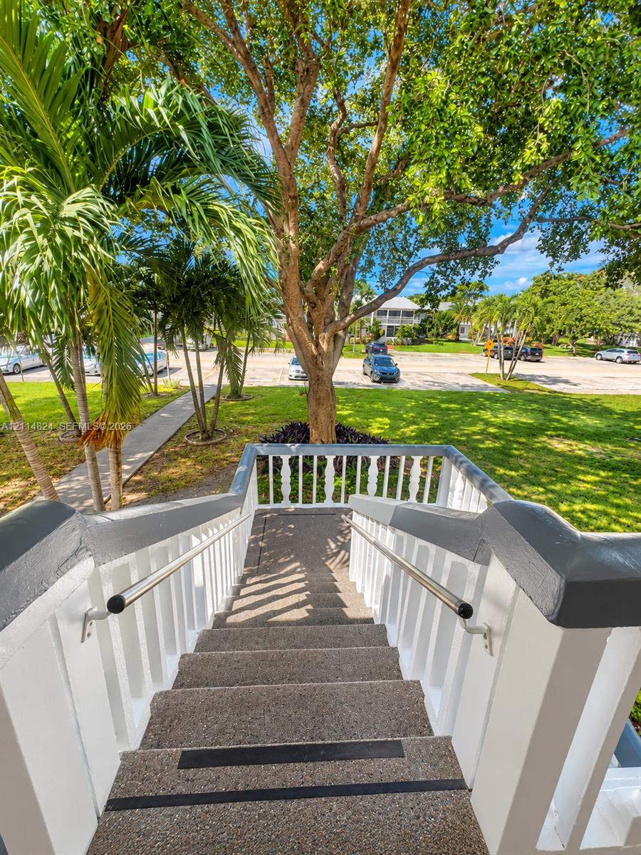 Exterior staircase featuring aggregate treads with integrated anti-slip strips, white balustrades, painted railings, and metal handrails