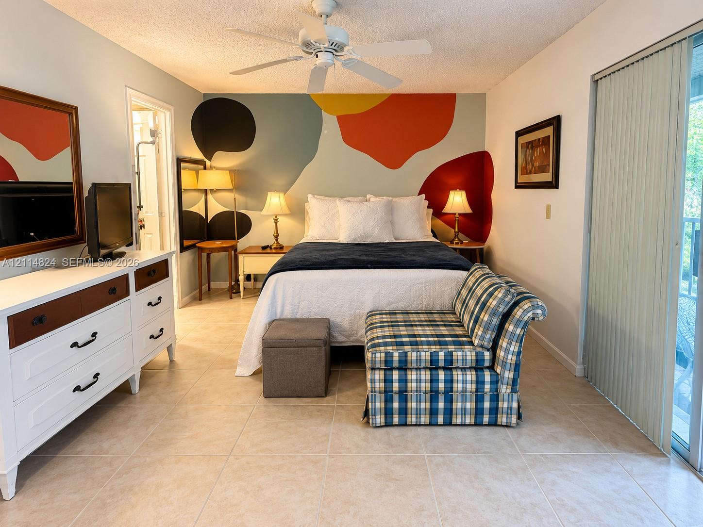 Room featuring neutral tile flooring, a white ceiling fan, and sliding glass doors with vertical blinds