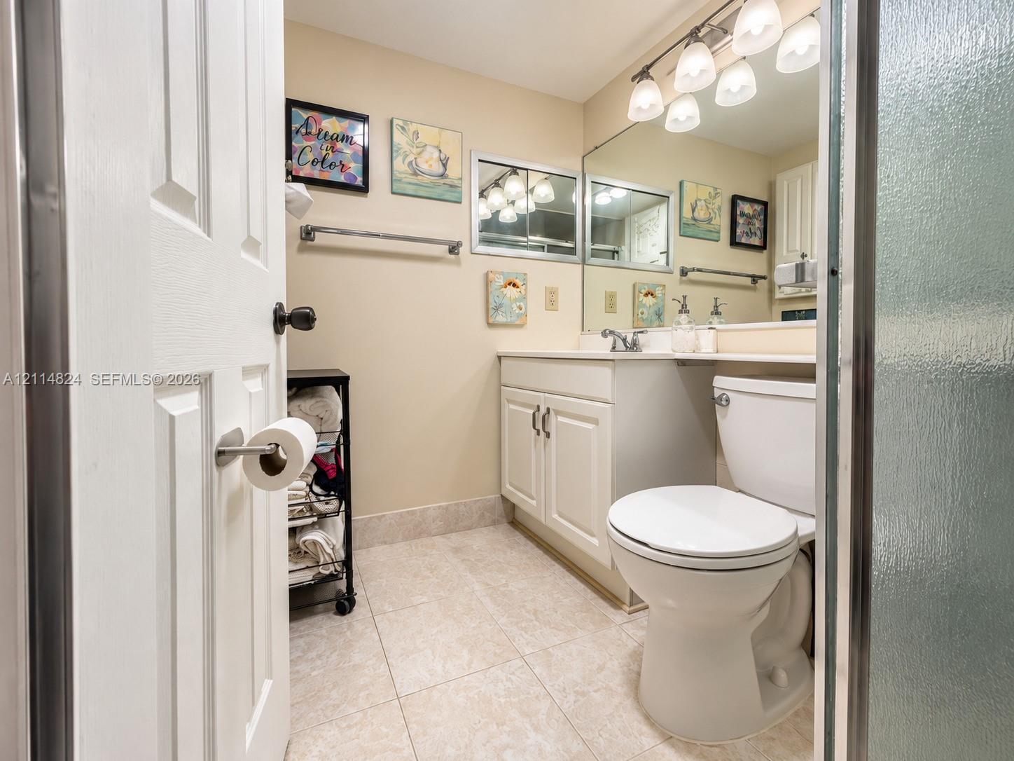 Bathroom featuring a vanity with white cabinetry, a large wall-mounted mirror, ceramic tile flooring, and a five-light overhead fixture