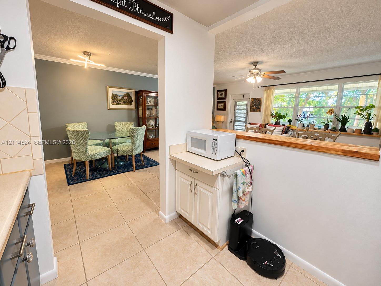 Kitchen featuring tile flooring, neutral cabinetry, and a natural wood-topped pass-through counter