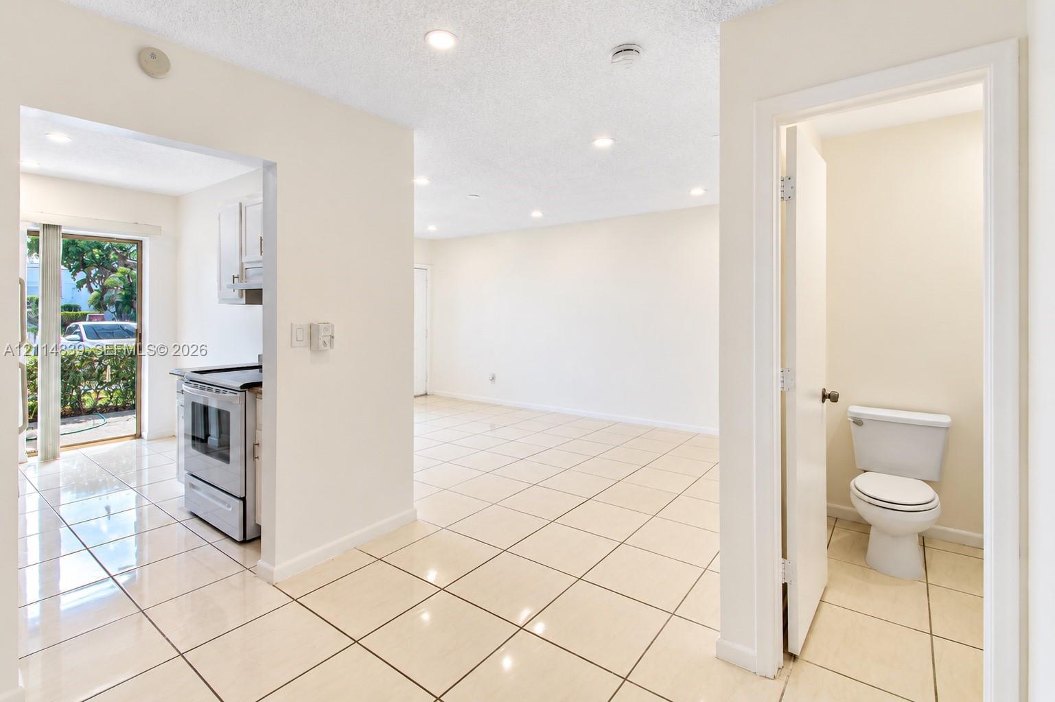 Neutral-toned ceramic tile flooring throughout, recessed lighting, and a compact bathroom featuring a standard porcelain toilet