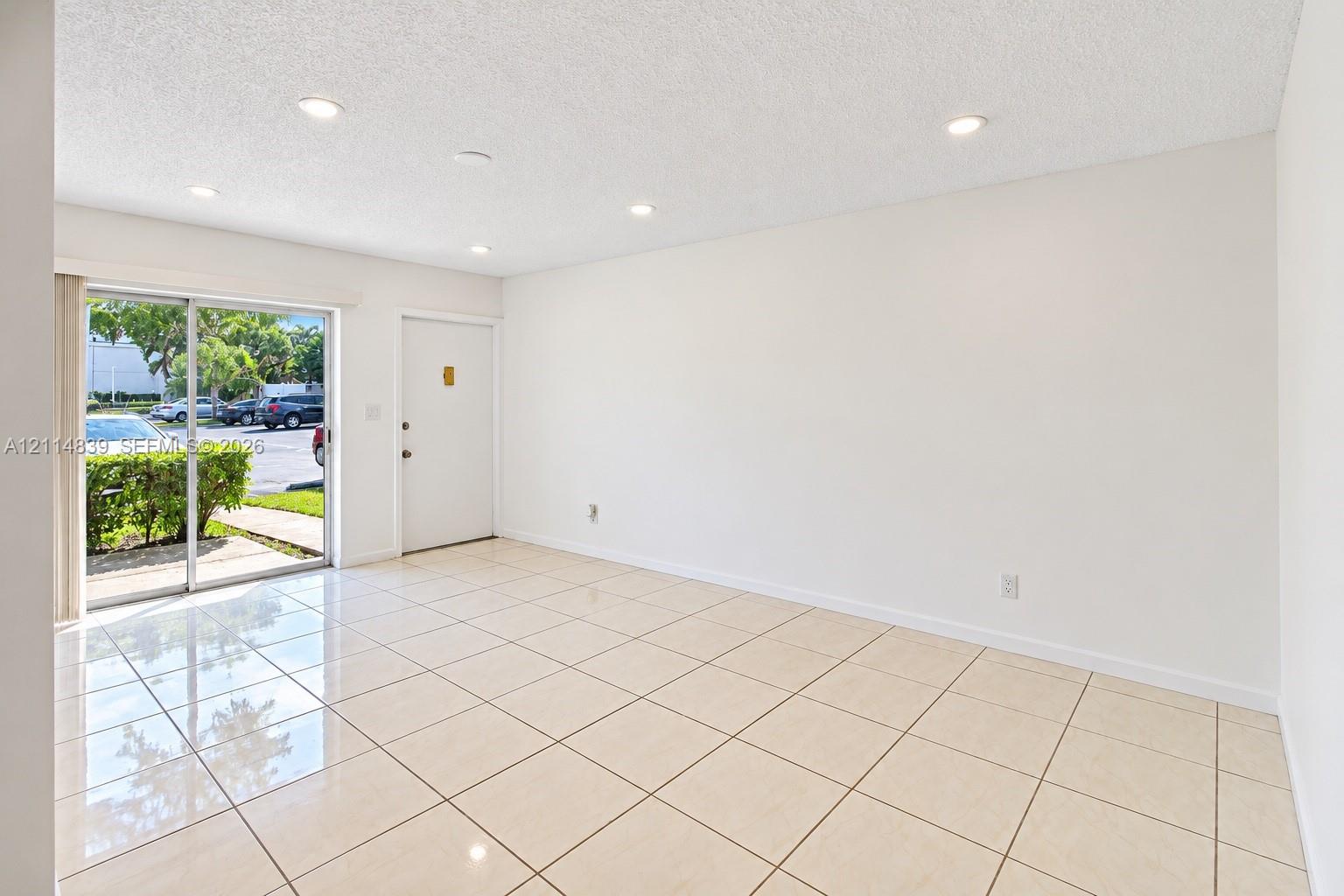 Interior featuring neutral tile flooring, recessed ceiling lighting, and sliding glass door access to the exterior