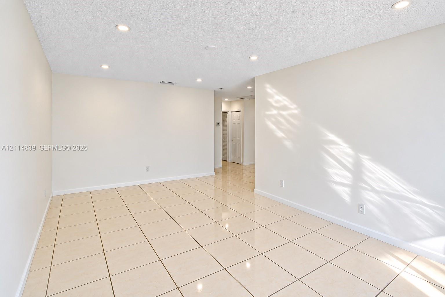 Neutral interior space featuring polished tile flooring, recessed lighting, and crisp, white-painted walls