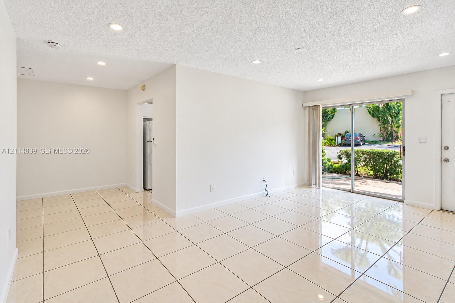 Living area featuring large-format tile flooring, recessed lighting, and a sliding glass door