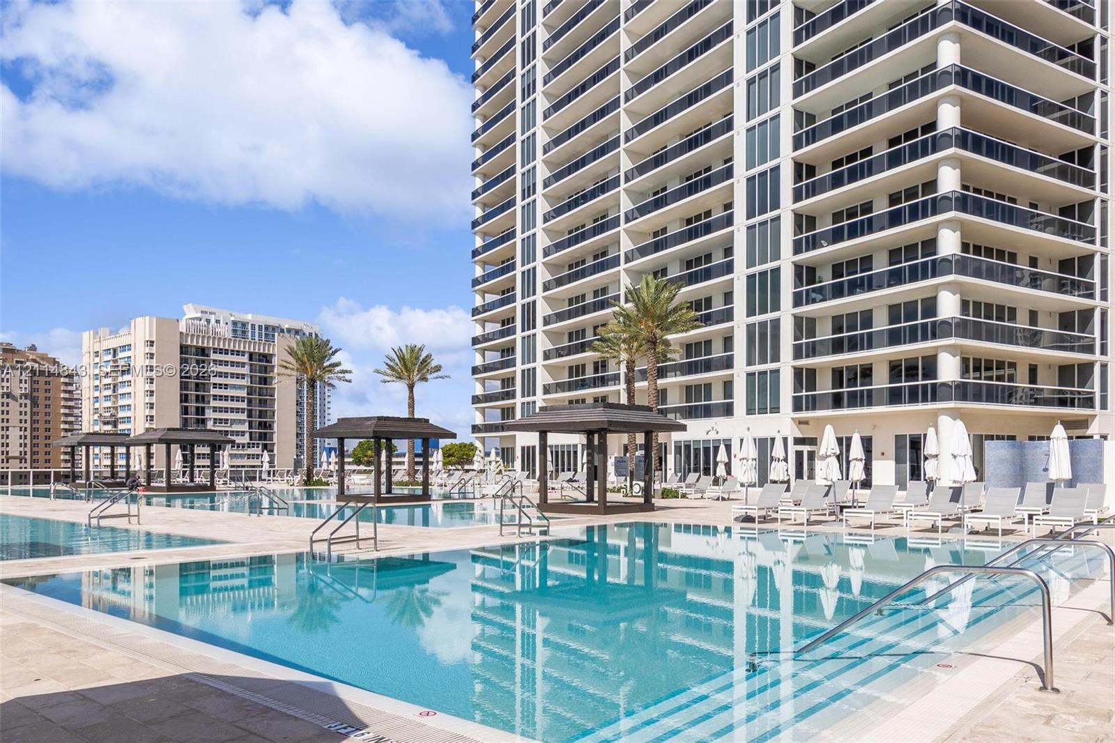 Multi-level outdoor pool deck featuring integrated shade structures, stone-paver decking, and metal handrails