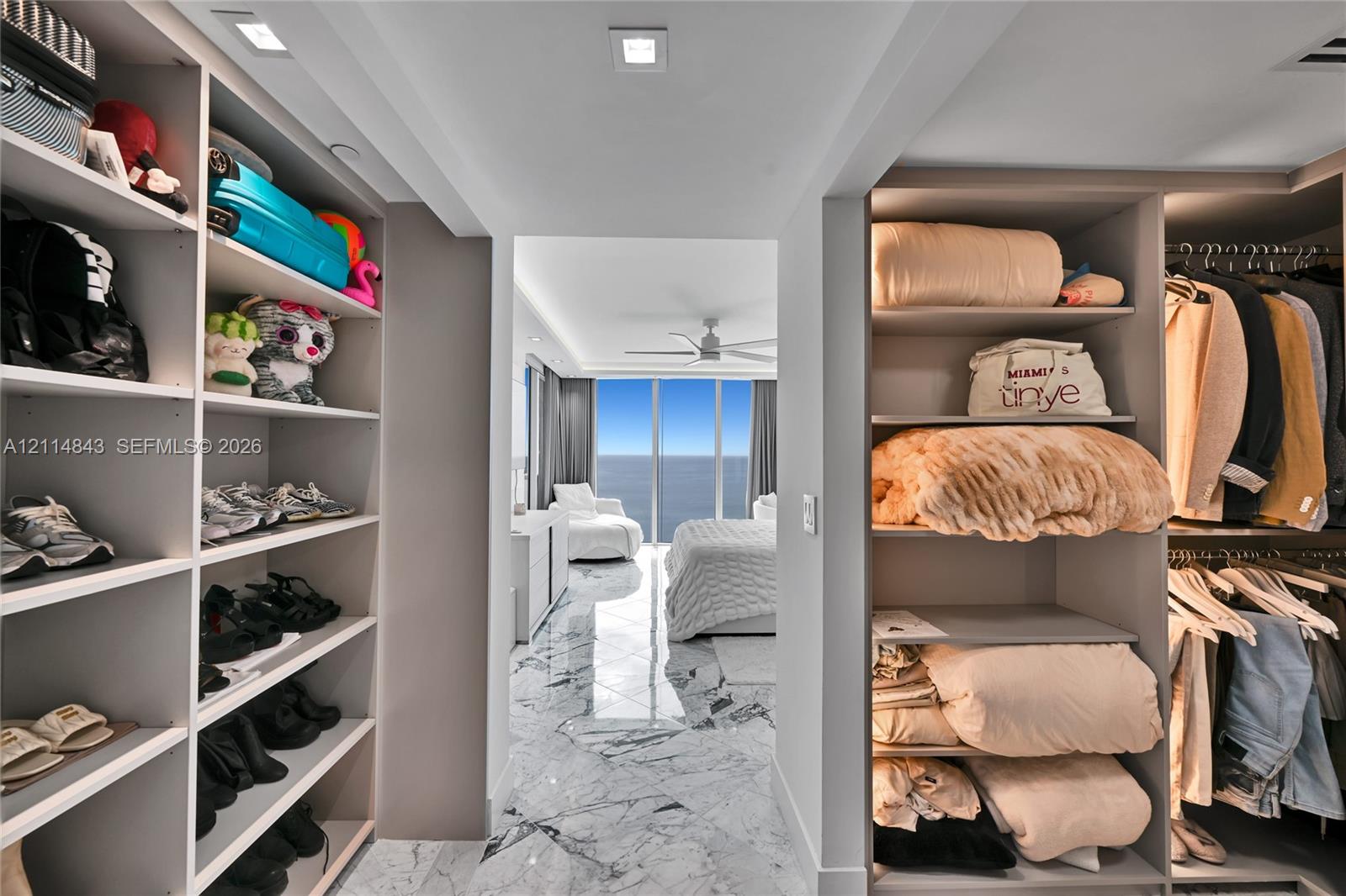 Walk-in closet with extensive custom shelving and integrated hanging rods, featuring stone-finish flooring throughout