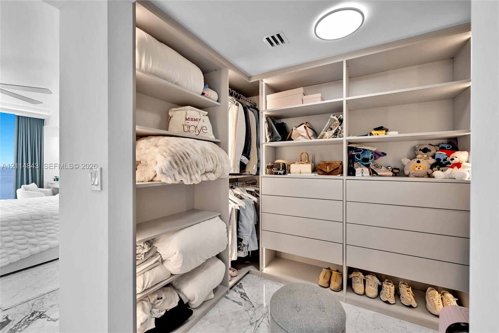 Custom walk-in closet featuring floor-to-ceiling built-in cabinetry, integrated LED shelf lighting, multiple soft-close drawers, and marble-finish flooring