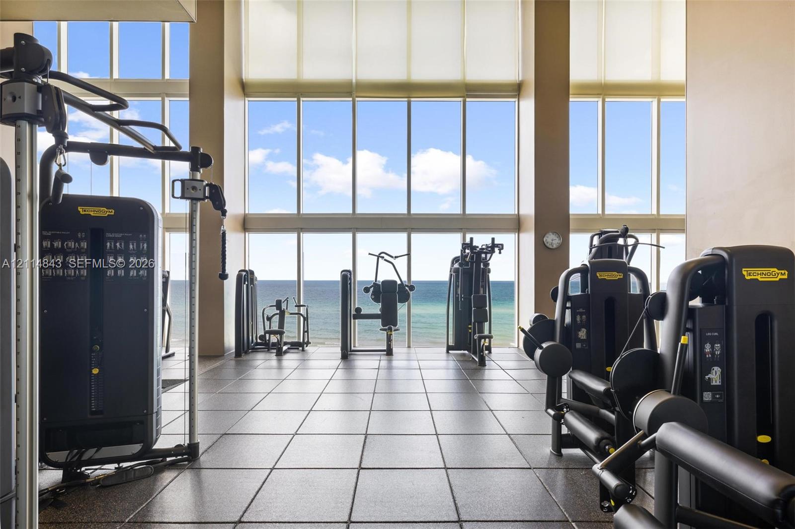Fitness center featuring floor-to-ceiling windows, large-format tile flooring, and direct ocean exposure