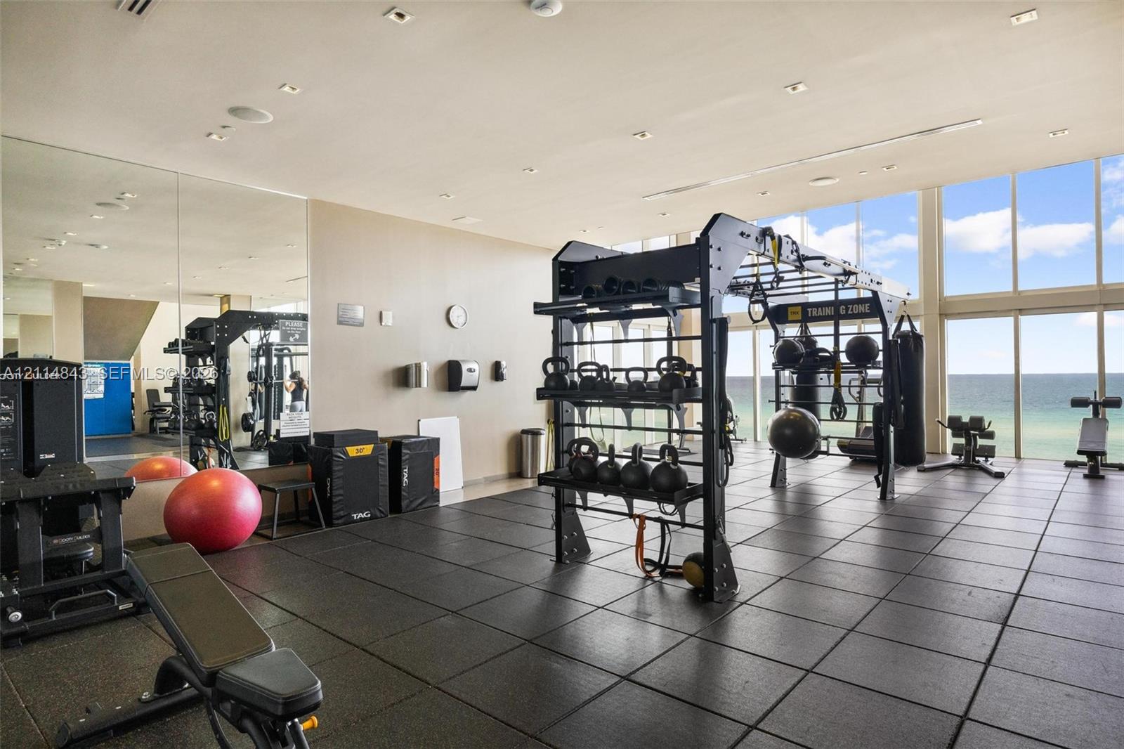 Fitness center featuring floor-to-ceiling windows, full-wall mirrors, and durable rubber flooring
