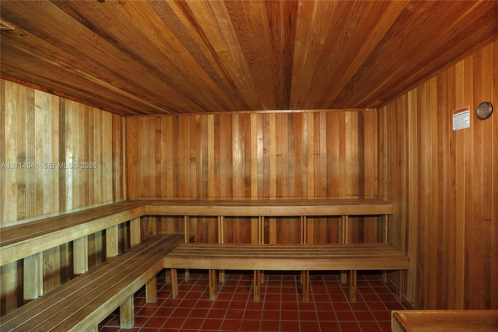 Sauna featuring tongue-and-groove wood paneling, multi-level built-in wood bench seating, and ceramic tile flooring