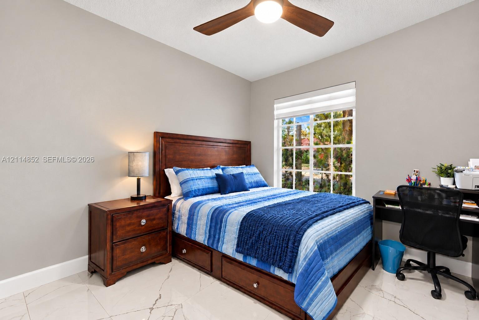 Neutral wall color, polished stone-finish flooring, and a multi-blade ceiling fan with integrated lighting