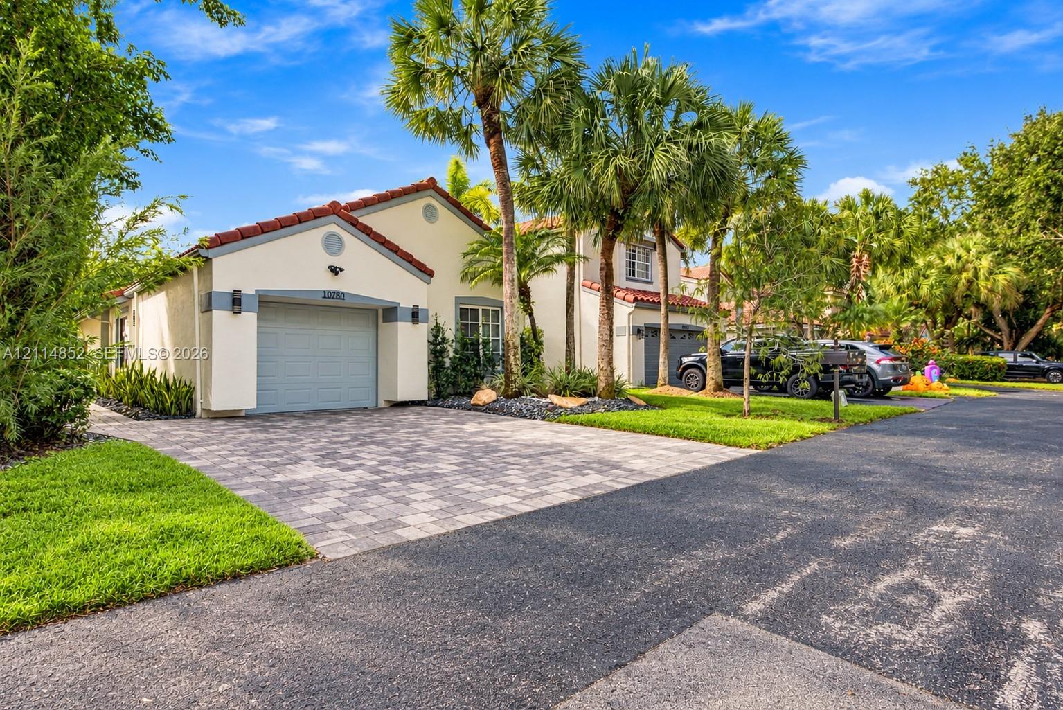 Stucco exterior featuring a red tile roof, single-car garage, and paver driveway