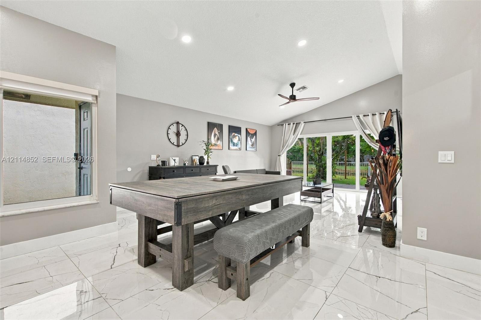 High-gloss, large-format tile flooring, vaulted ceilings, recessed lighting, ceiling fan, and multi-panel sliding glass doors