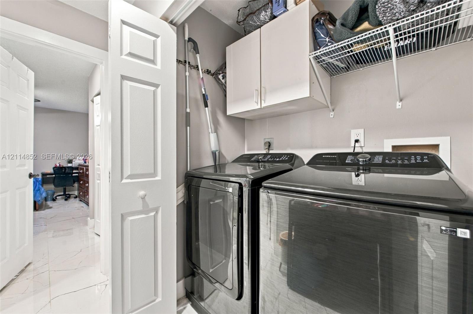 Laundry area featuring white cabinetry, wire shelving, and neutral wall tones