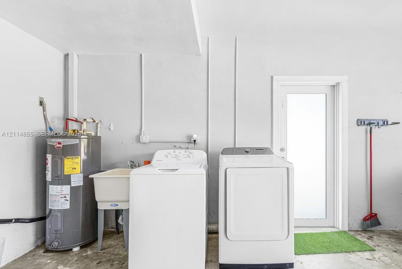 Utility area featuring a floor-mounted water heater, a basin sink with a chrome faucet, and exterior door access