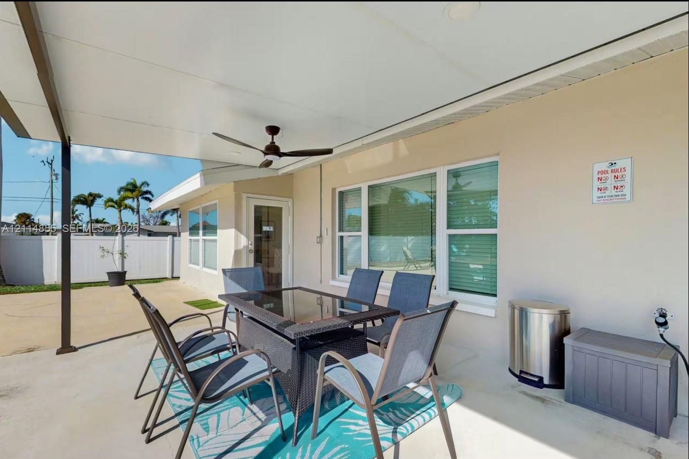 Covered concrete patio featuring a ceiling-mounted fan and exterior privacy fencing
