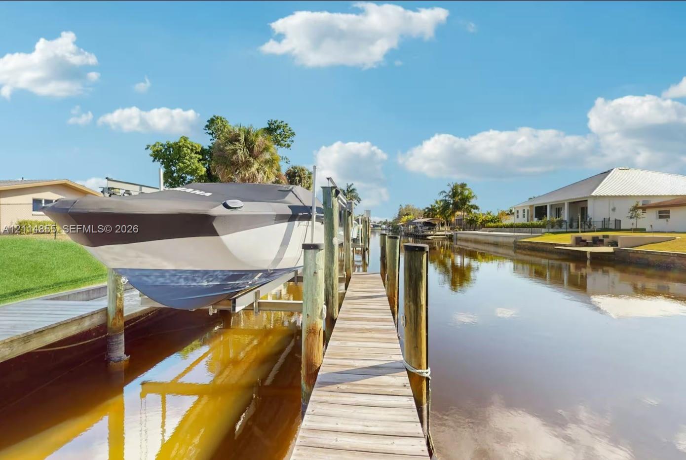 Private waterfront dock featuring wooden decking, sturdy pilings, and a mechanical boat lift