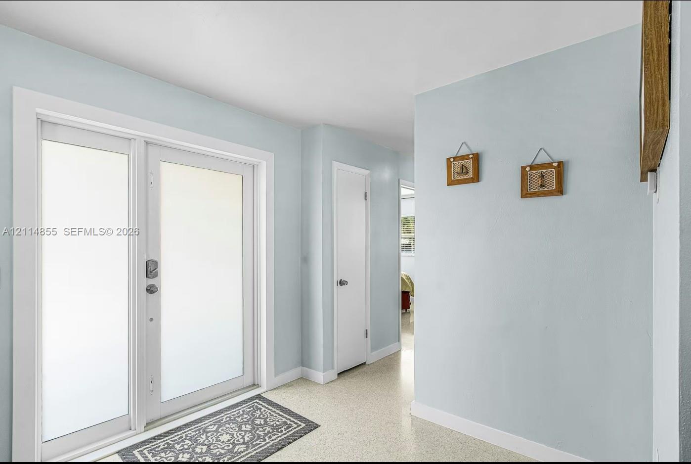 Double-entry door featuring frosted glass panels and neutral-toned interior walls with smooth-finish flooring