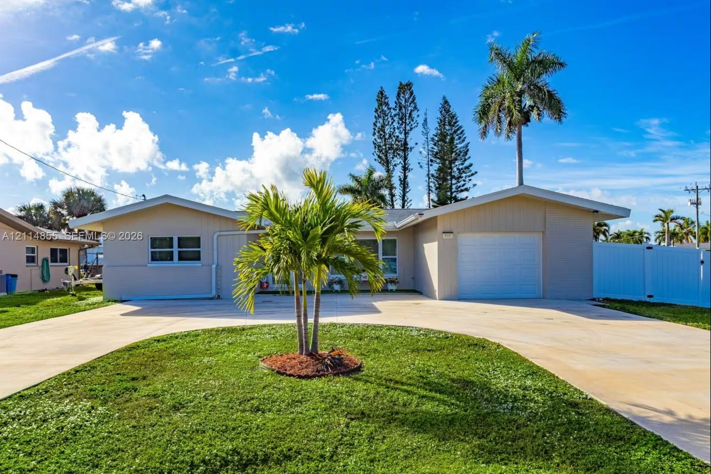 Single-story residence featuring a stucco exterior, concrete driveway, attached garage, and landscaping with mature palm trees