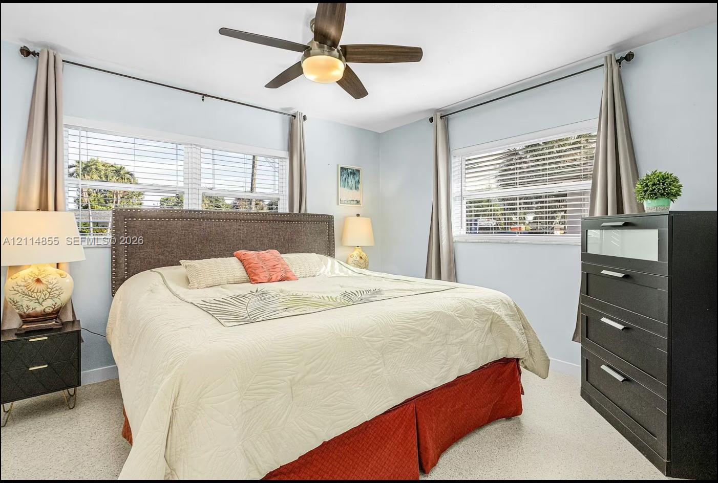 Room featuring neutral-toned carpeting, multi-pane windows with horizontal blinds, and a ceiling-mounted fan with integrated lighting