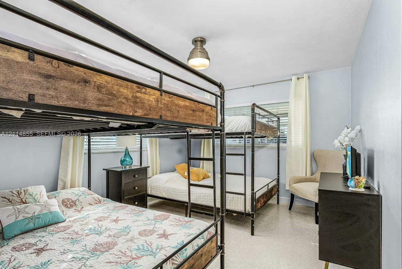 Neutral walls, horizontal window blinds, and overhead industrial-style flush mount lighting