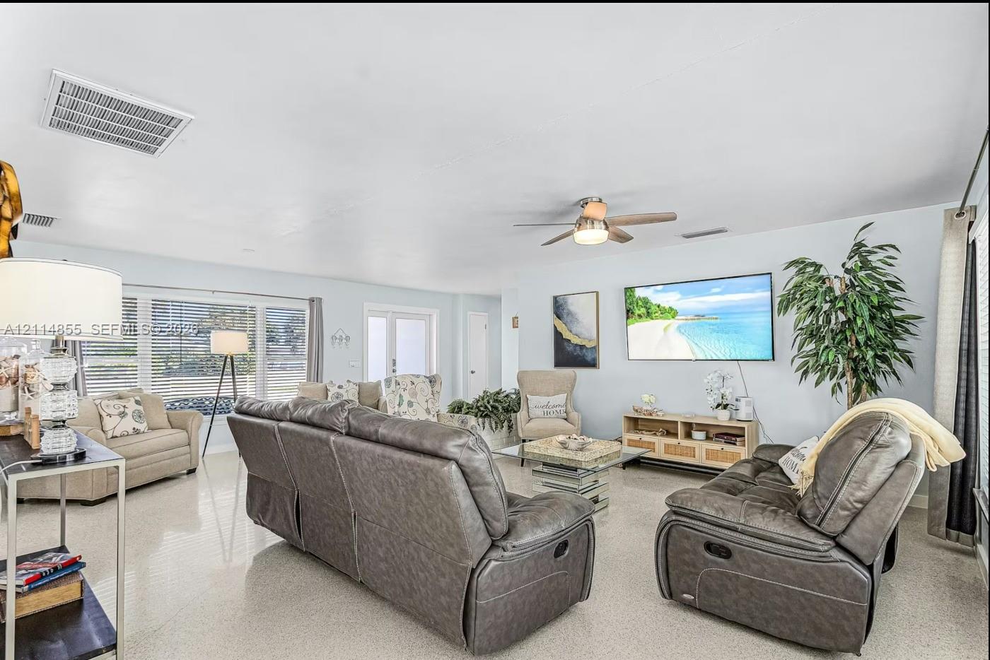 Living area featuring large-format tile flooring, a ceiling fan with integrated lighting, and expansive windows